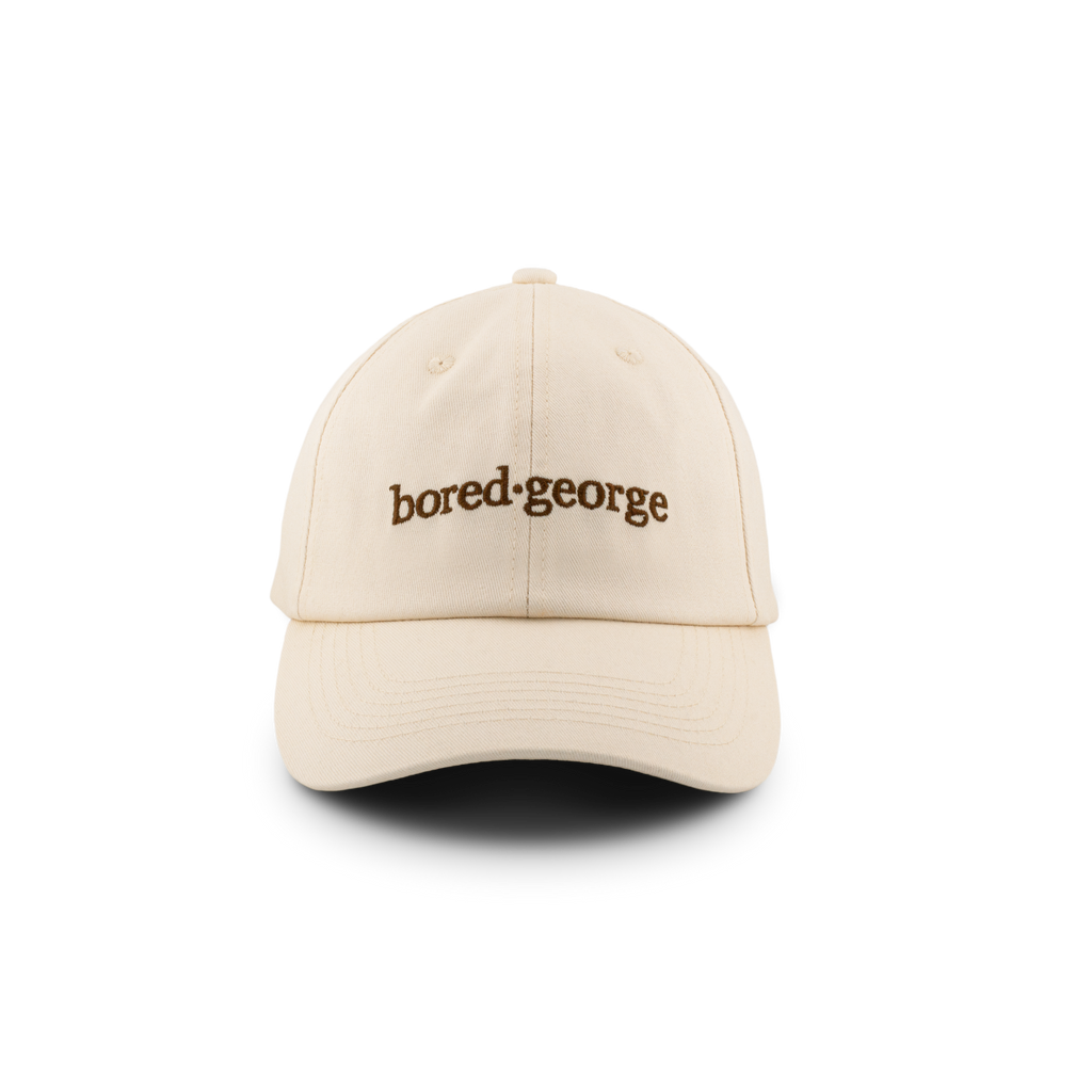 A beige baseball cap with the text 'bored.george' printed on the front.