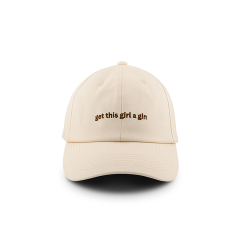 A beige baseball cap with text embroidered on the front that says "get this girl a gin"