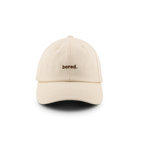 A beige baseball cap with the word 'bored.' embroidered on the front.