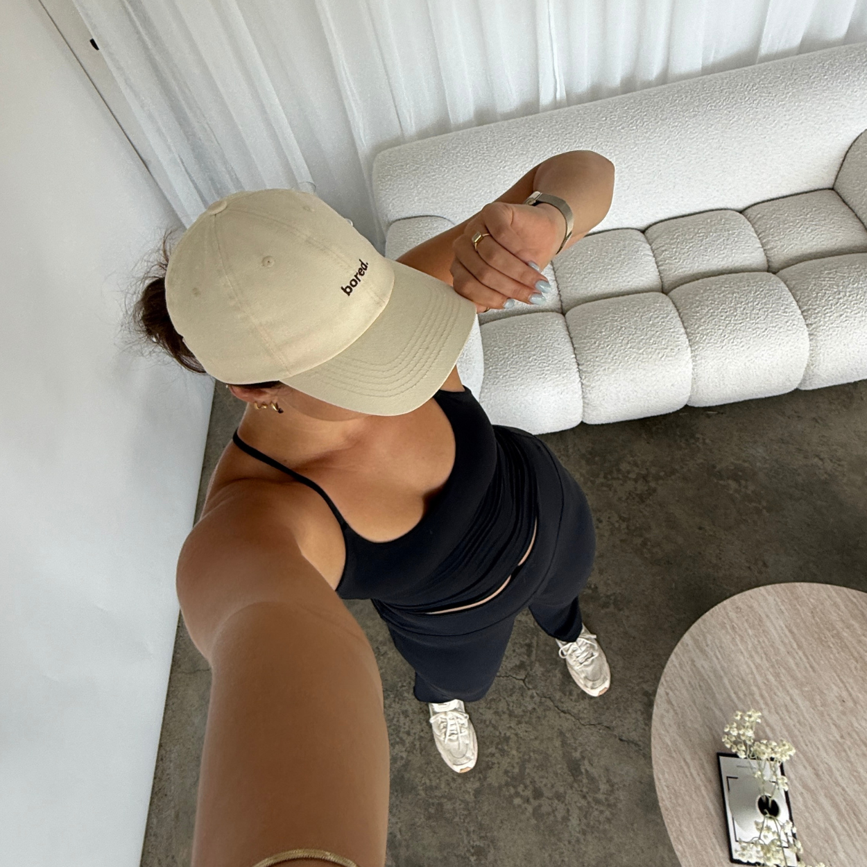 Woman wearing activewear in a beige baseball cap embroidered with "bored" text
