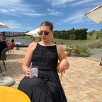 Woman in black dress wearing Miu Miu style cat eye polarised sunglasses with green lenses - collaboration with fashion designer Caitlin Crisp