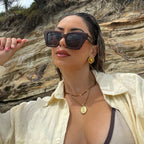 Woman on the beach wearing brown shimmer square oversized polarised timeless Bored George sunglasses