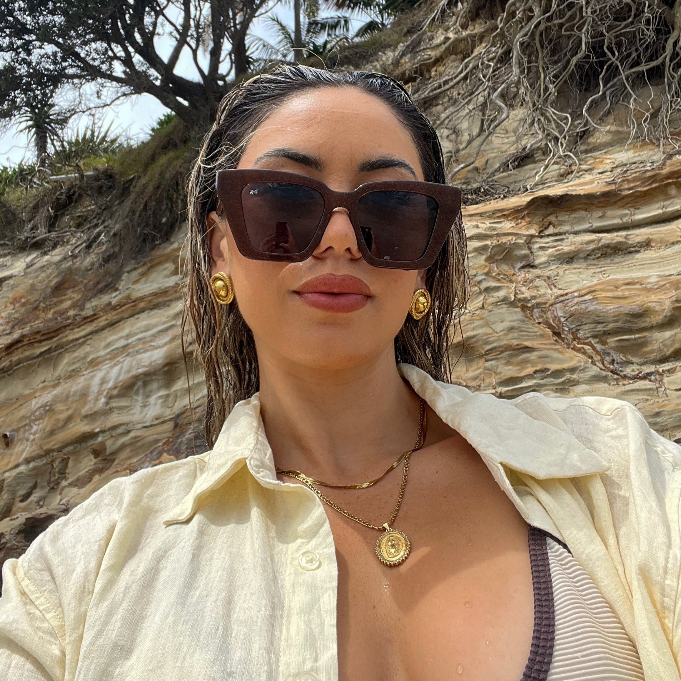 Woman on beach wearing best-selling brown shimmer oversized polarised Bored George sunglasses